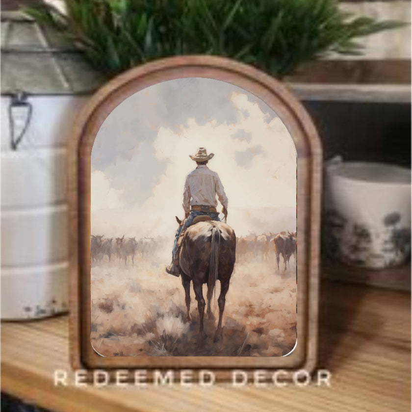 Decorative wall art with a cowboy on horseback in a wooden frame, featuring the brand 'Redeemed Decor'.