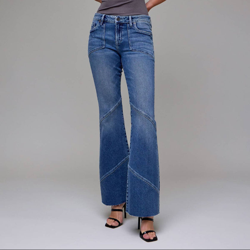 Woman wearing a gray sleeveless top and blue jeans against a plain background