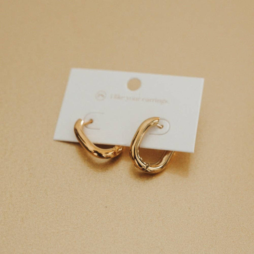Gold hoop earrings on a white card against a beige background
