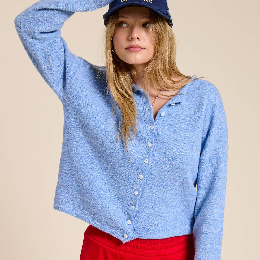 Woman wearing a blue shirt and red pants with a cap on a beige background
