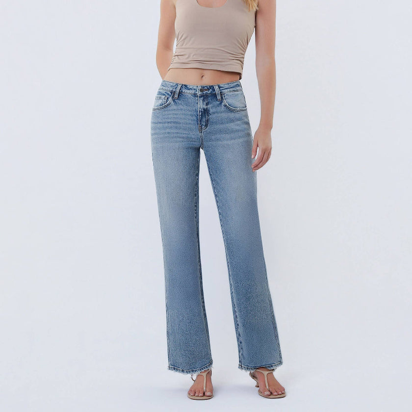 Woman wearing a beige tank top and light blue jeans on a white background