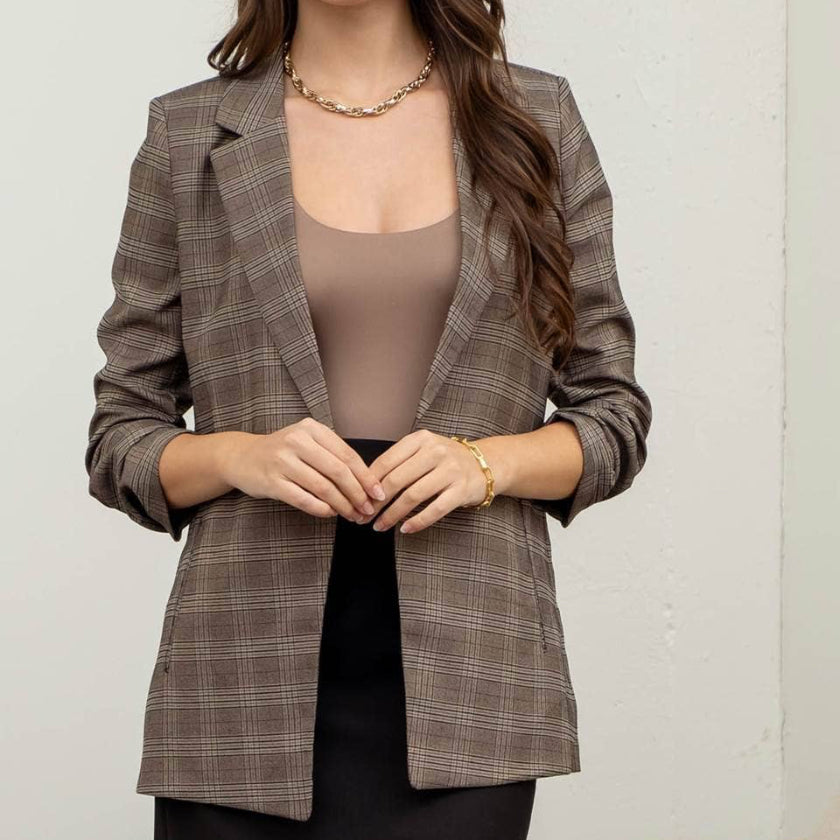 Woman wearing a plaid blazer over a beige top against a white background